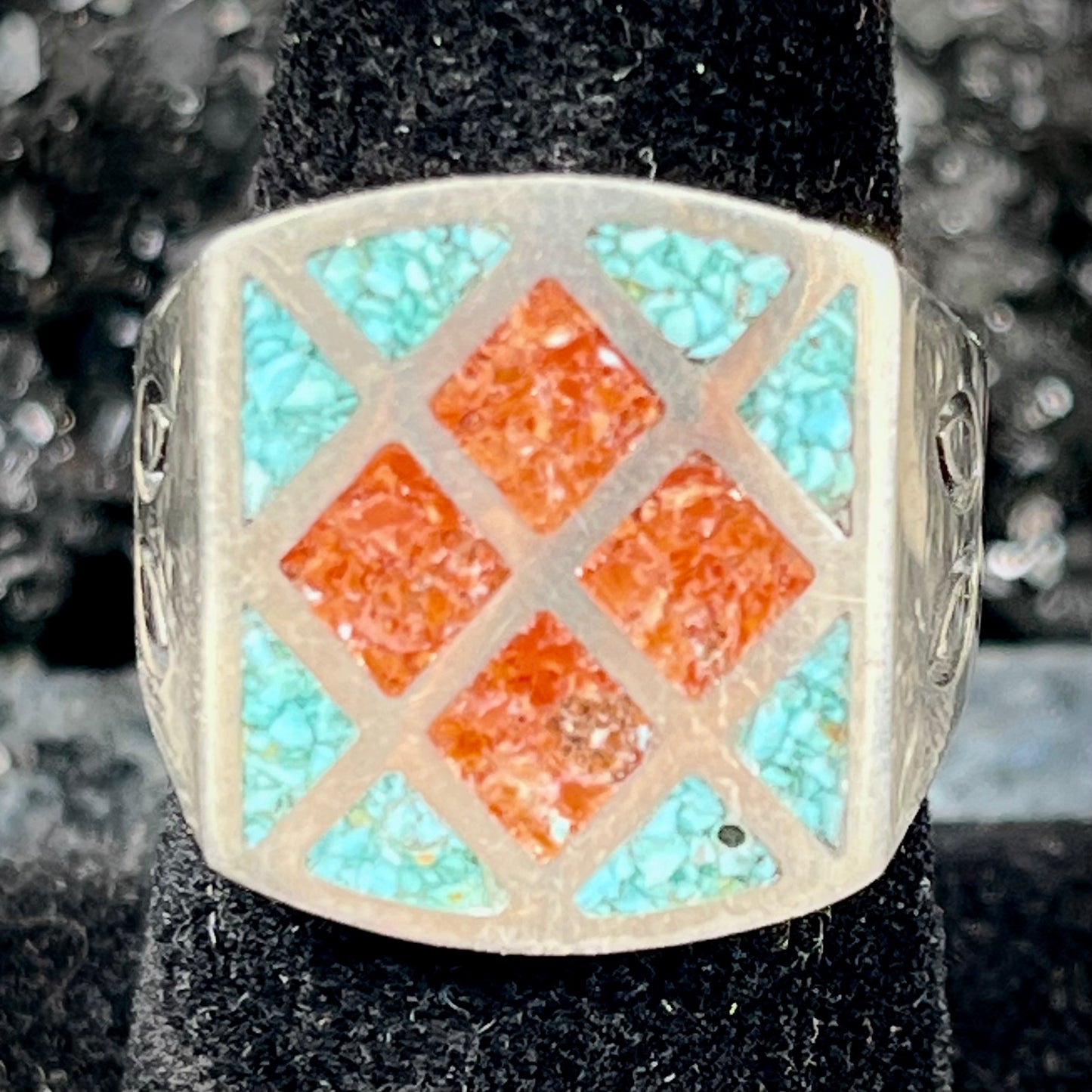 A men's sterling silver inlay ring set with sections of crushed blue turquoise and crushed red coral.