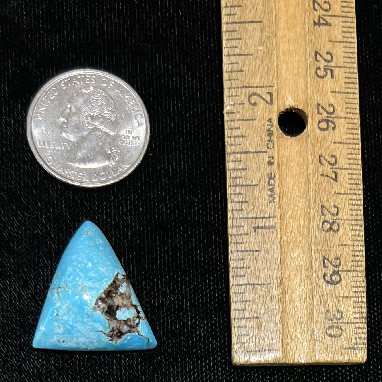 A triangular cabochon cut turquoise stone from the Valley Blue mine in Lander County, Nevada. The stone has a black matrix.