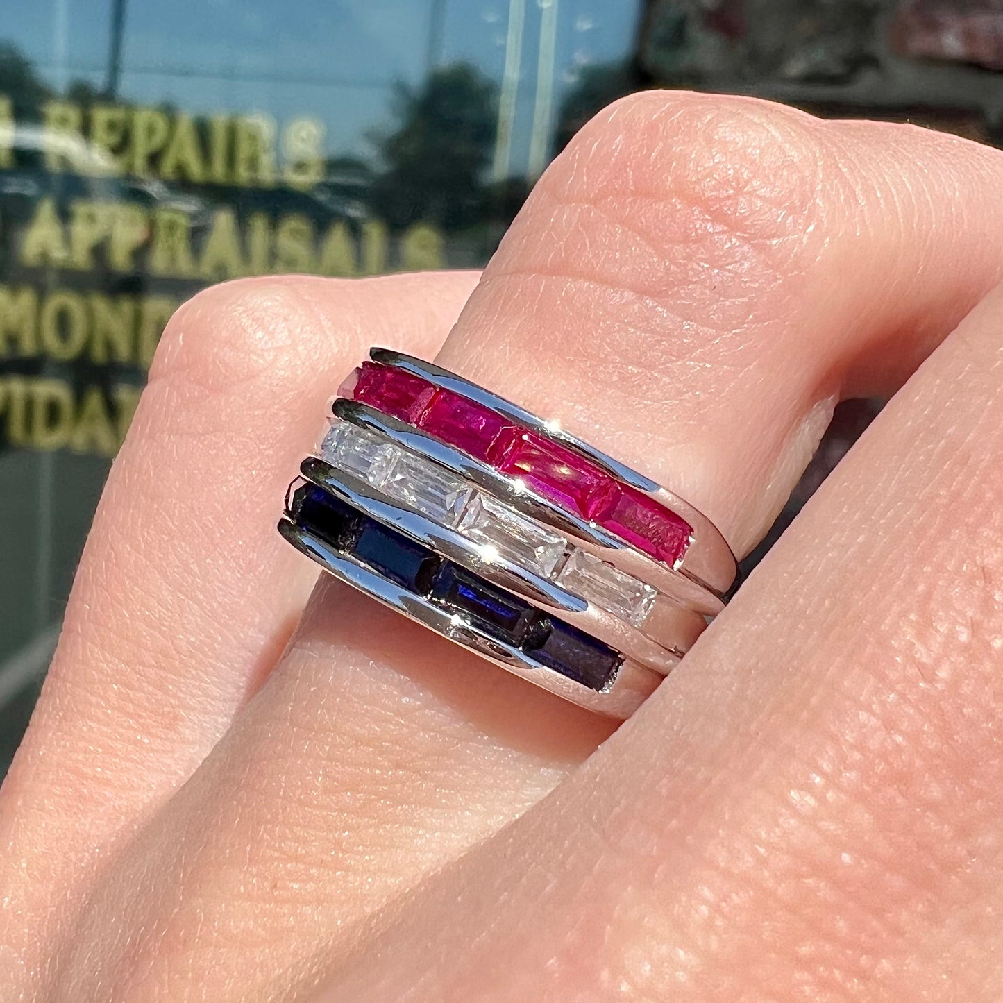 A silver ring set with red, white, and blue baguette cut stones. The gallery features two stars.