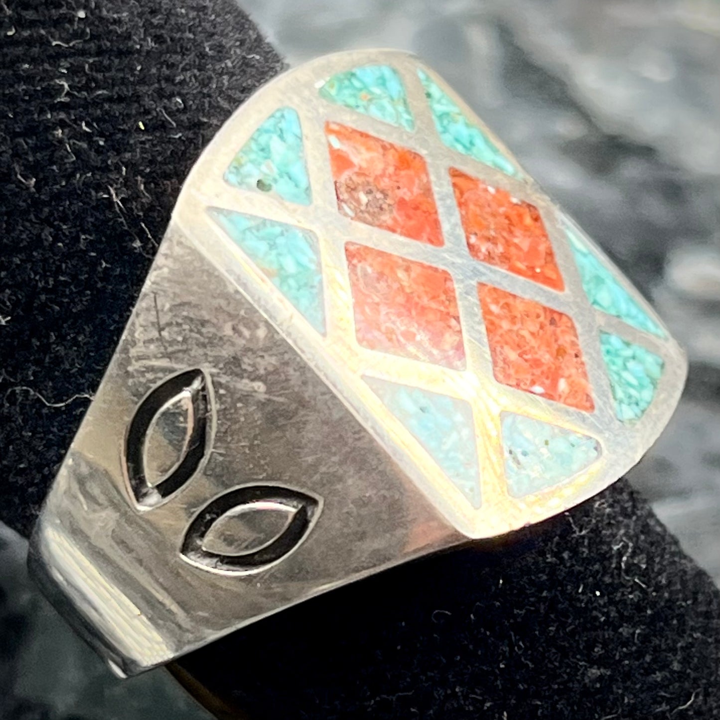 A men's sterling silver inlay ring set with sections of crushed blue turquoise and crushed red coral.