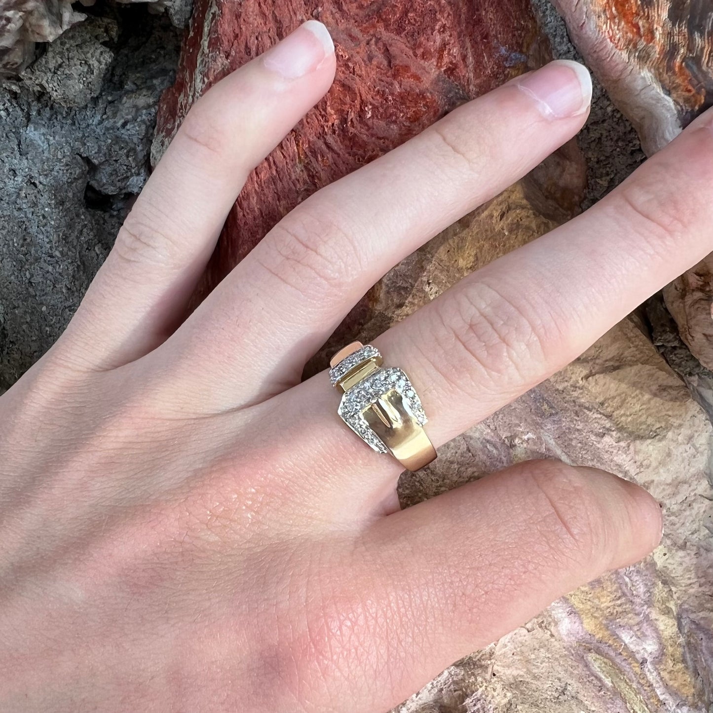 A yellow gold buckle ring set with round diamonds in the buckle.