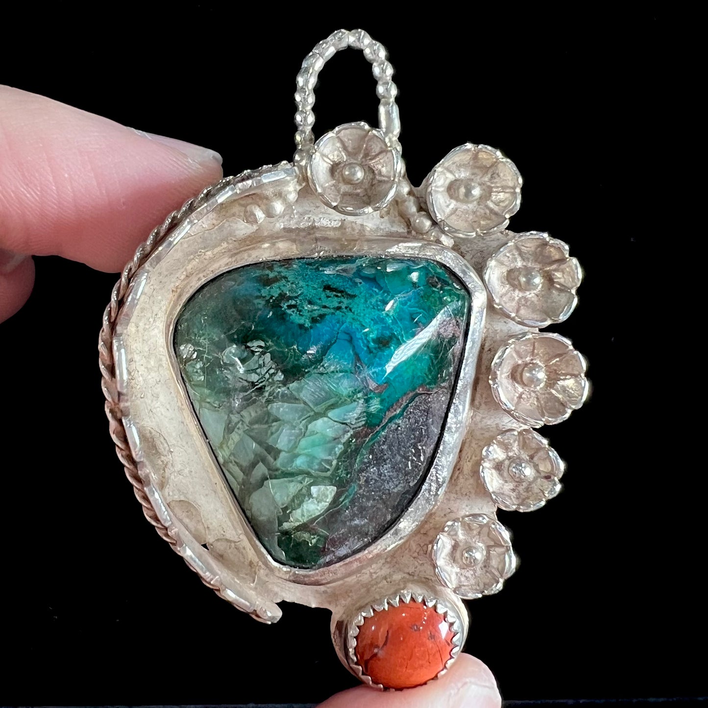 A sterling silver Navajo-style pendant set with chrysocolla and red jasper stones.