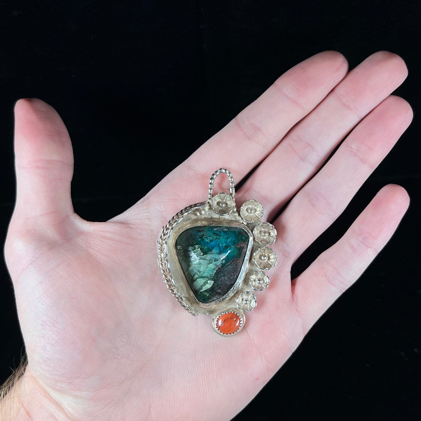 A sterling silver Navajo-style pendant set with chrysocolla and red jasper stones.