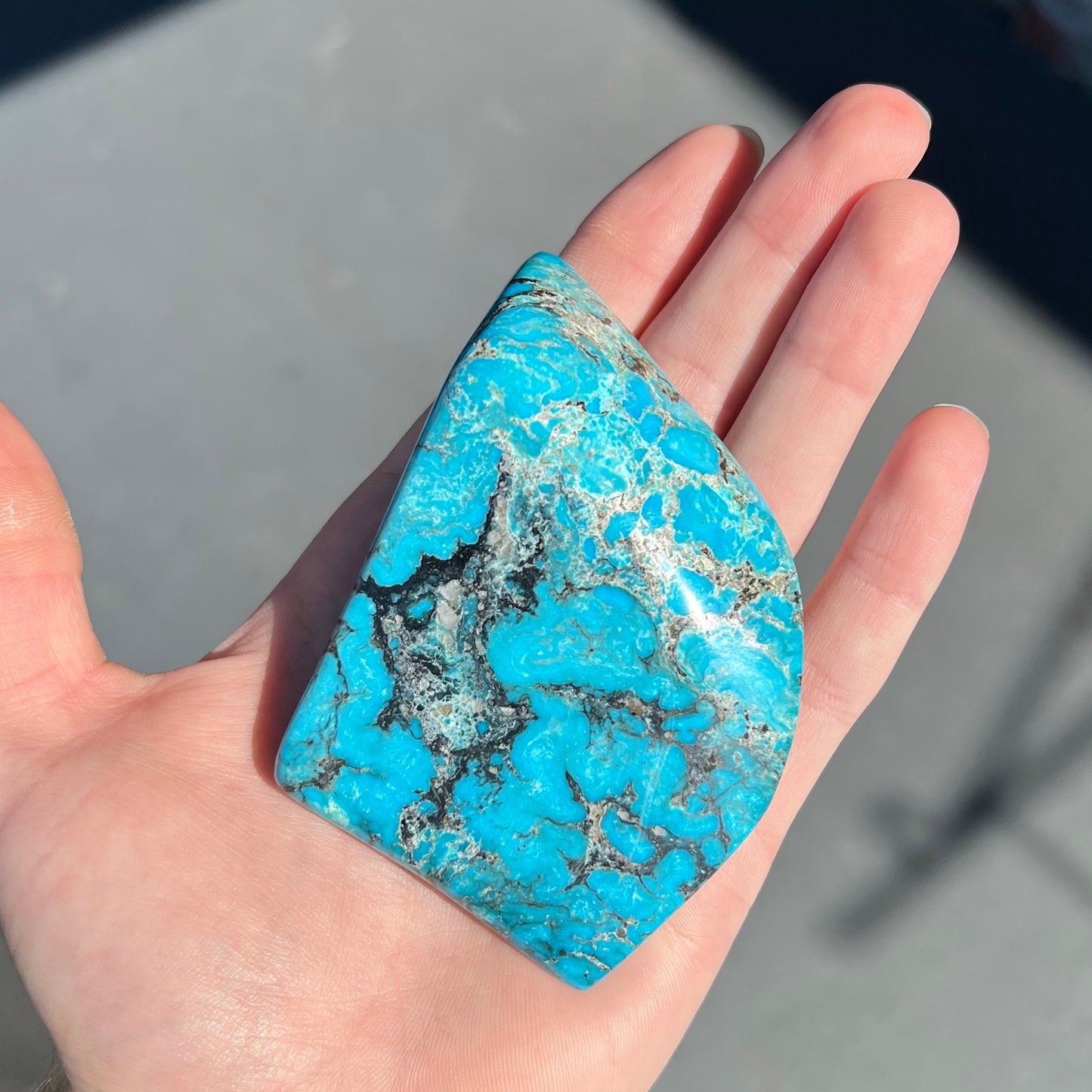 A large polished piece of Kingman turquoise. The stone is blue with black veining.