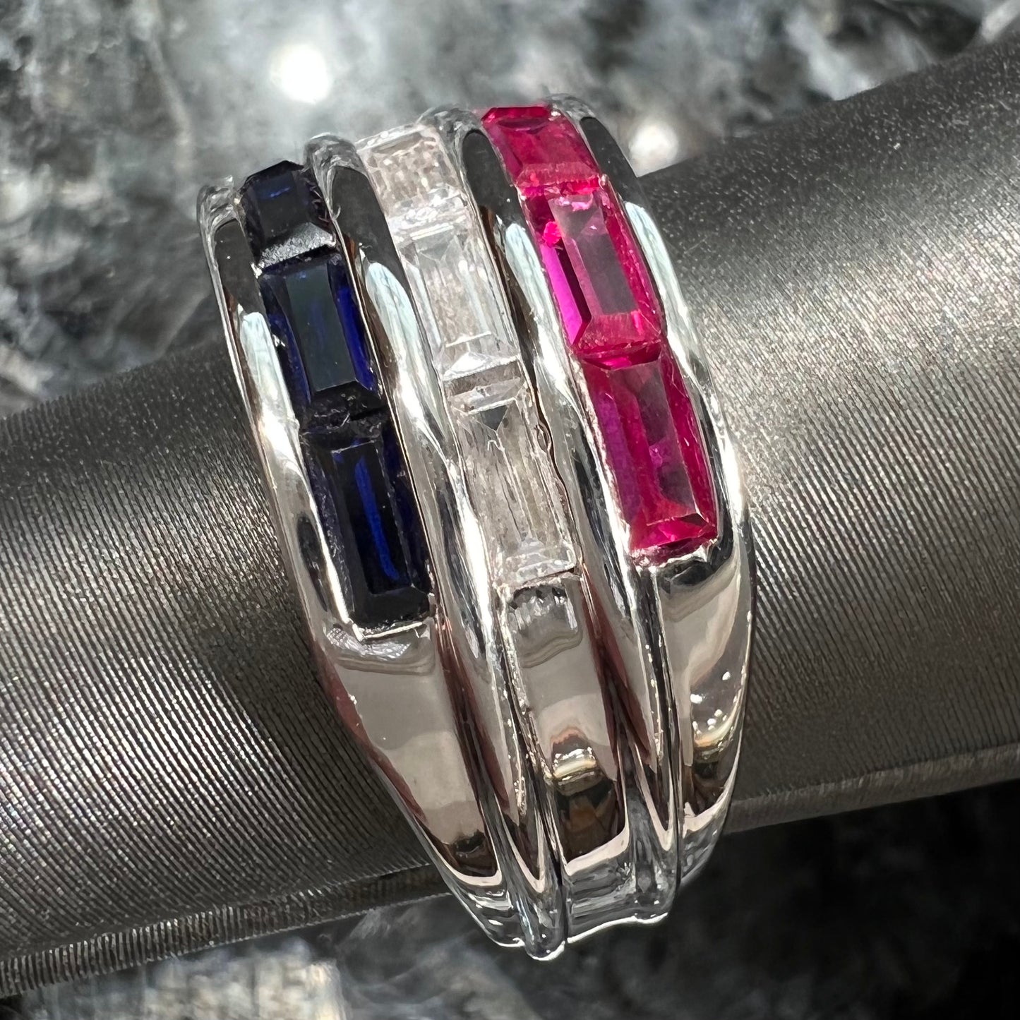 A silver ring set with red, white, and blue baguette cut stones. The gallery features two stars.