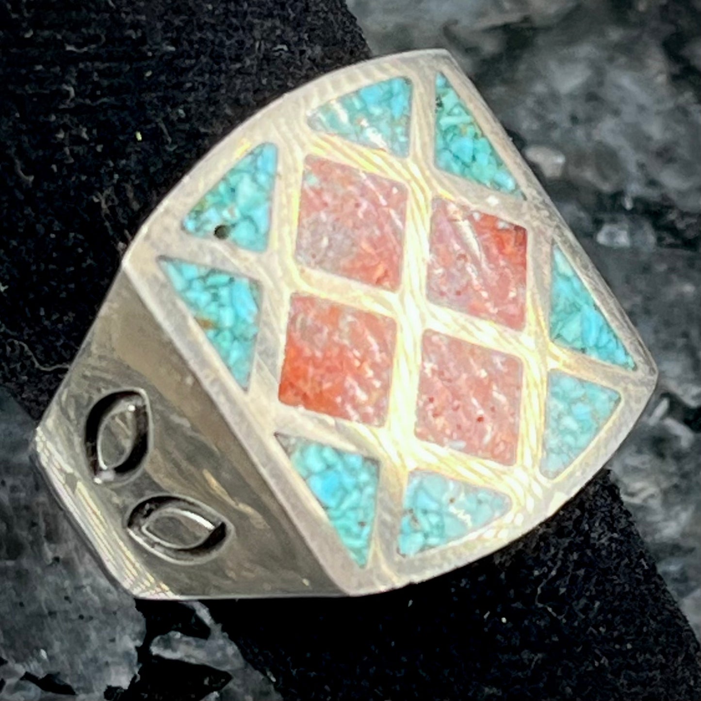 A men's sterling silver inlay ring set with sections of crushed blue turquoise and crushed red coral.