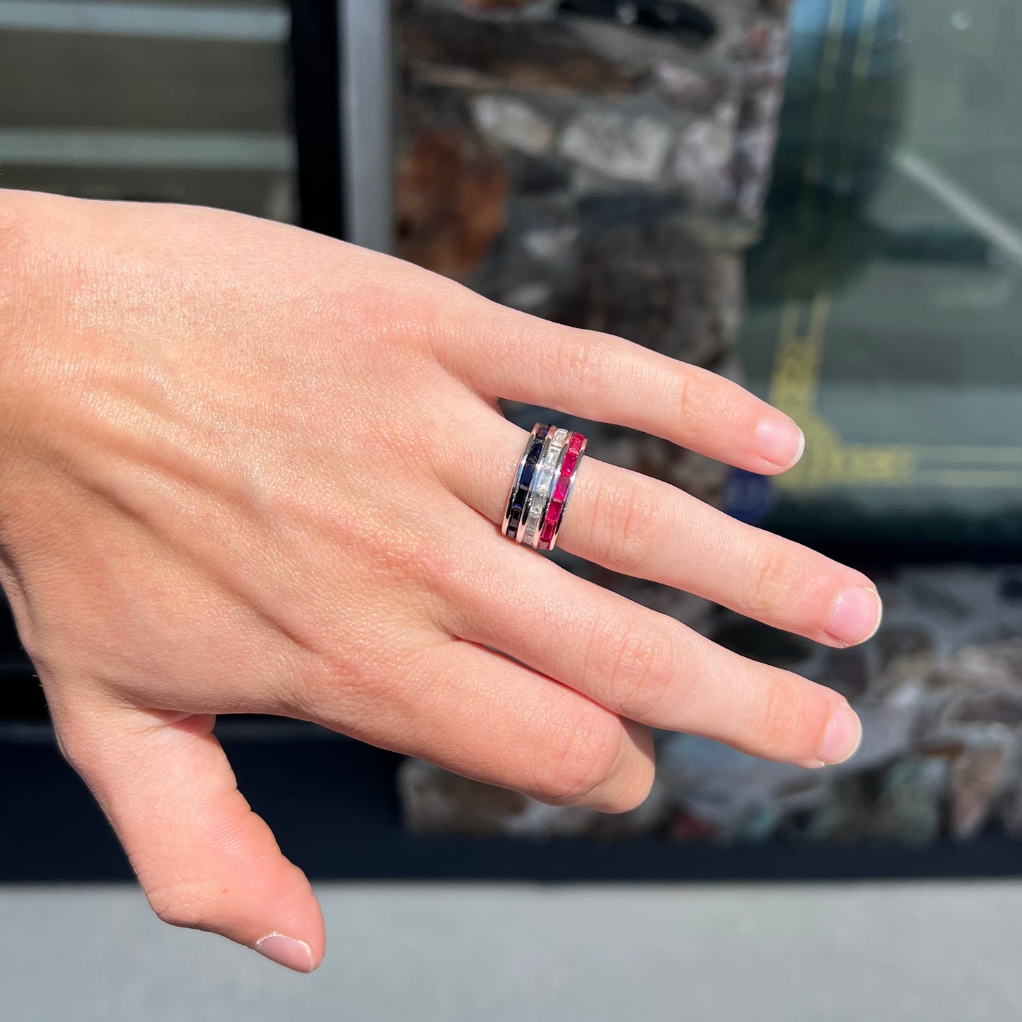 A silver ring set with red, white, and blue baguette cut stones. The gallery features two stars.