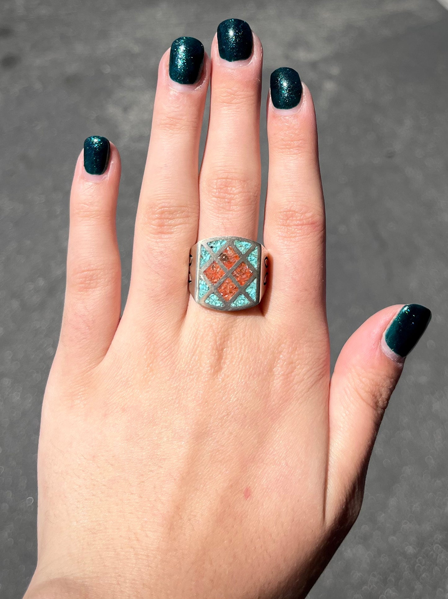 A men's sterling silver inlay ring set with sections of crushed blue turquoise and crushed red coral.