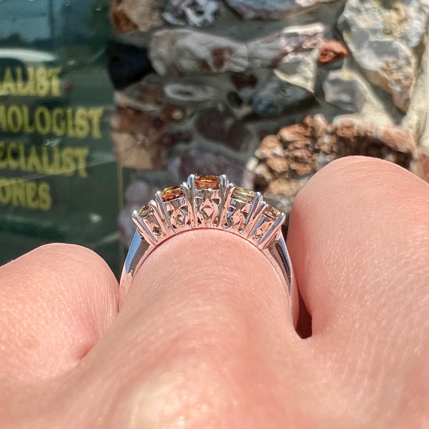 A sterling silver ring set with five faceted oval and round andalusite stones.