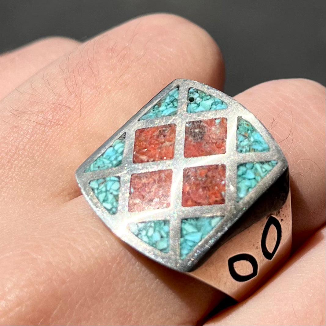 A men's sterling silver inlay ring set with sections of crushed blue turquoise and crushed red coral.