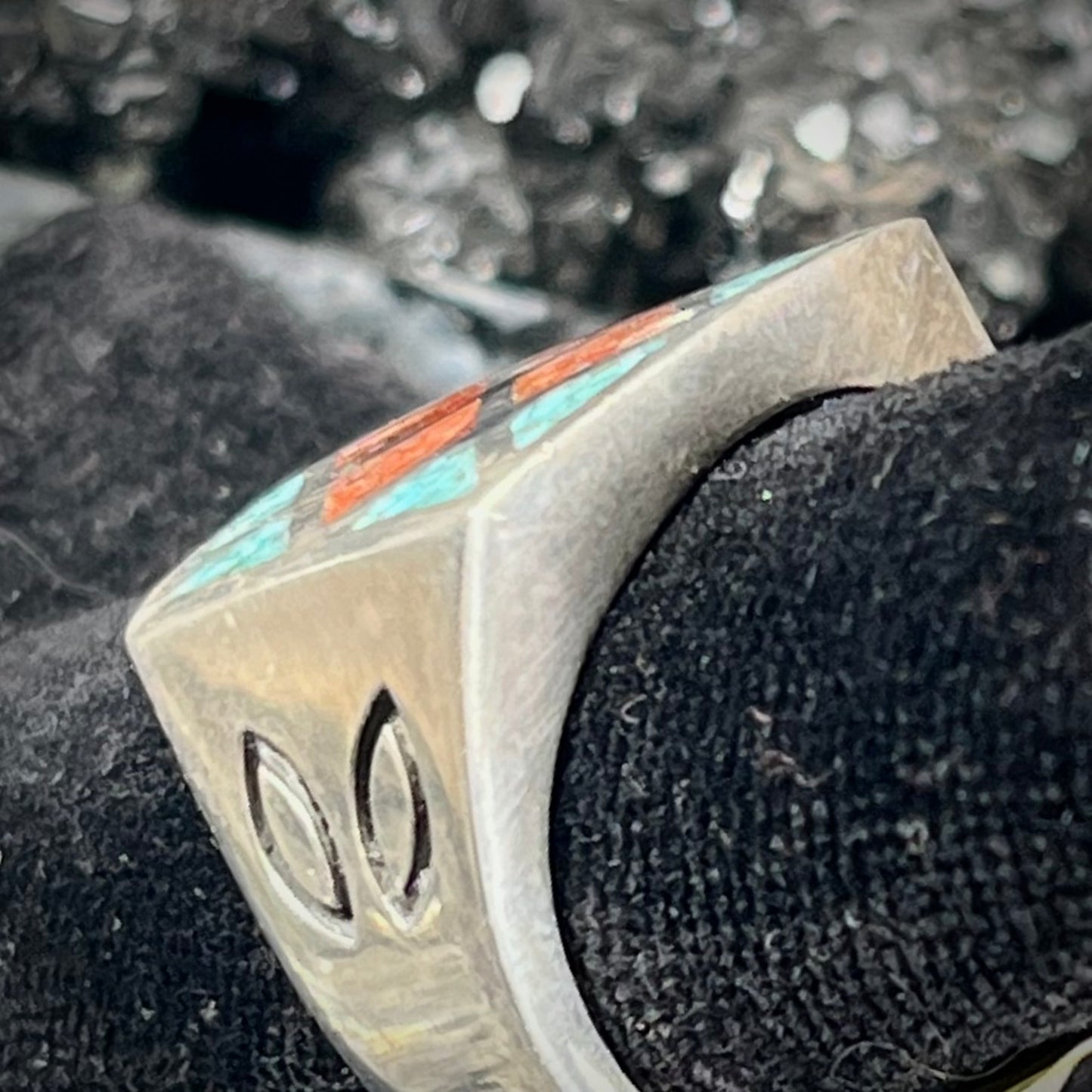 A men's sterling silver inlay ring set with sections of crushed blue turquoise and crushed red coral.