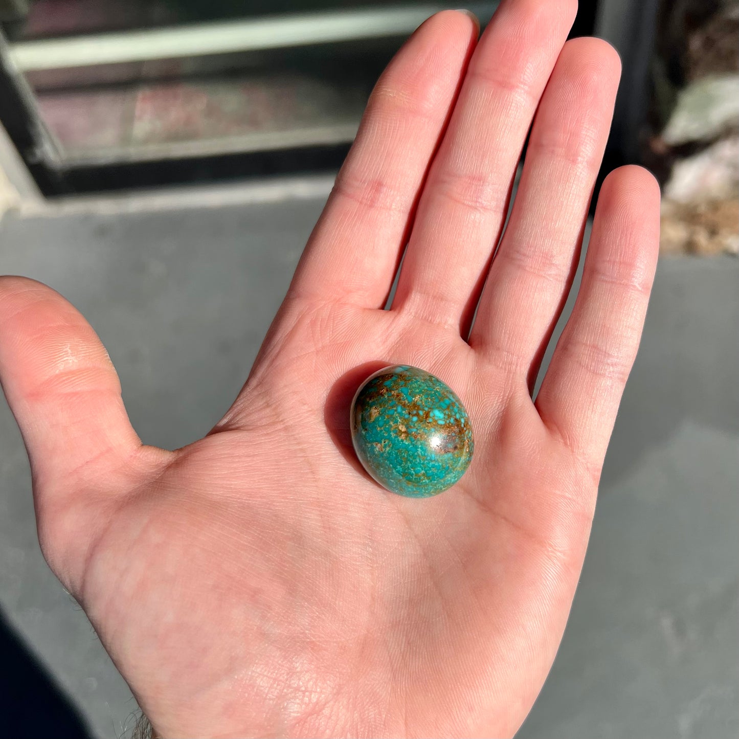 An oval cabochon cut green Royston turquoise with brown matrix.