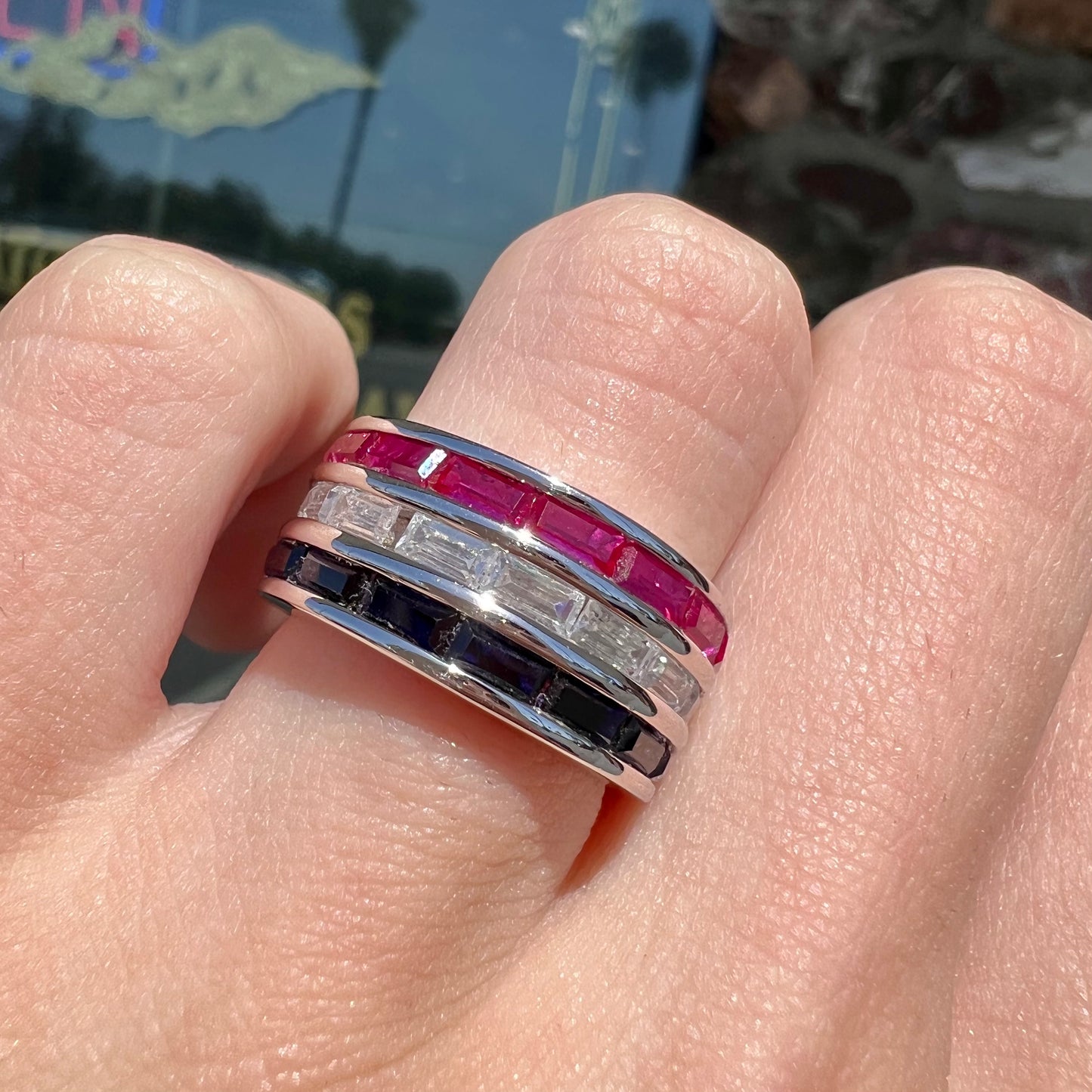 A silver ring set with red, white, and blue baguette cut stones. The gallery features two stars.