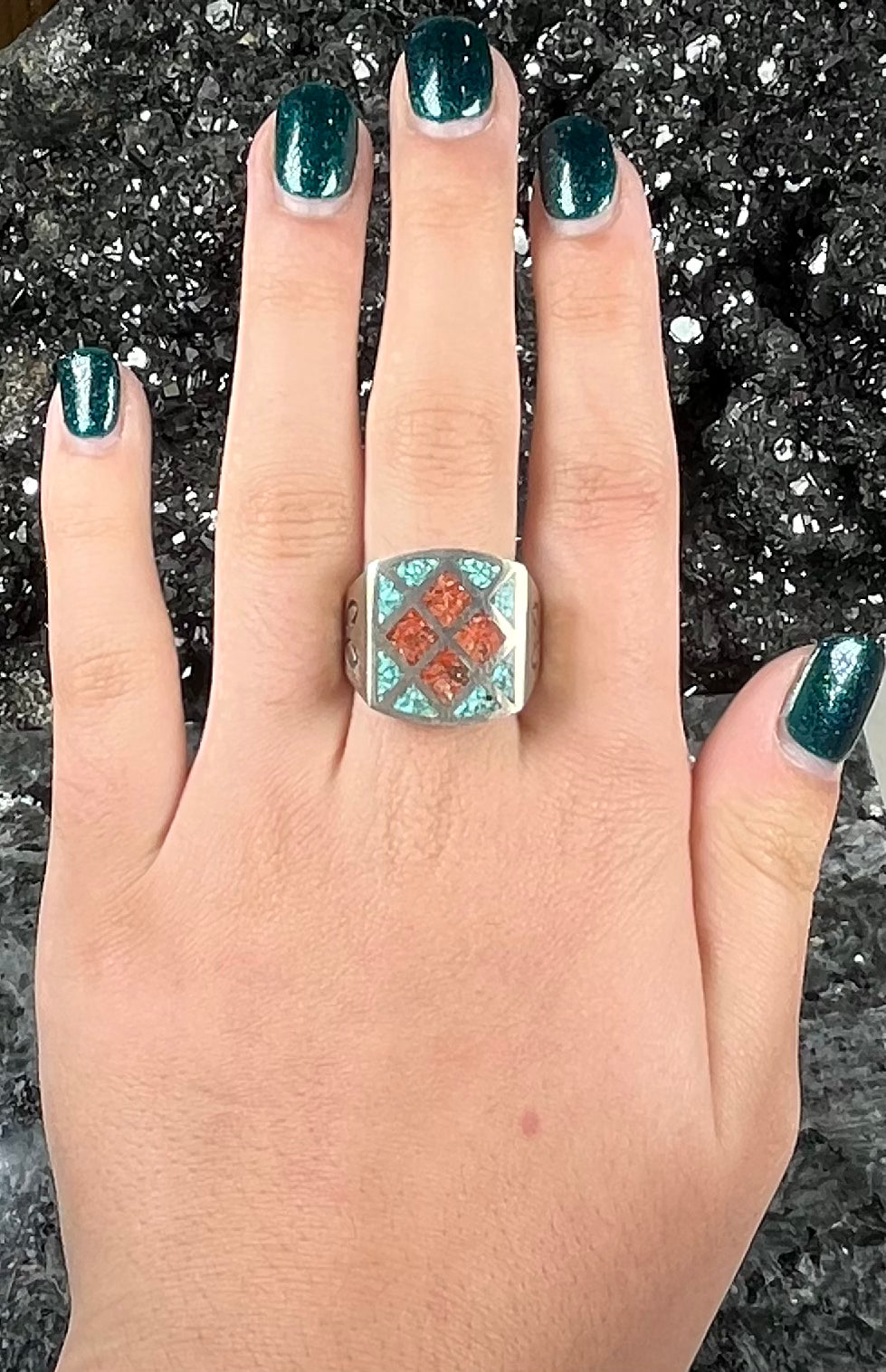 A men's sterling silver inlay ring set with sections of crushed blue turquoise and crushed red coral.