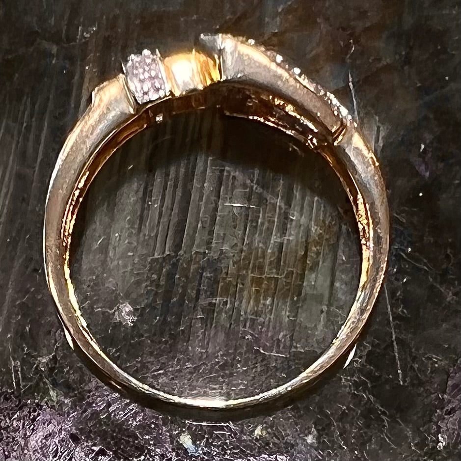 A yellow gold buckle ring set with round diamonds in the buckle.