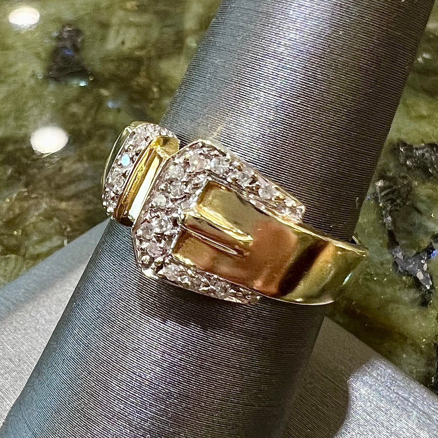 A yellow gold buckle ring set with round diamonds in the buckle.