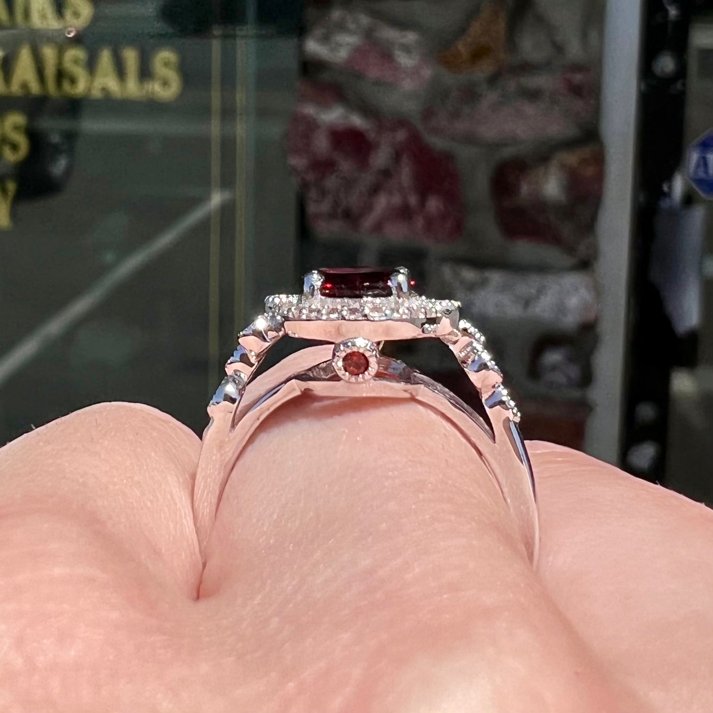 A silver garnet and CZ halo ring. The center stone is a red almandine garnet, and the side garnets are orange.