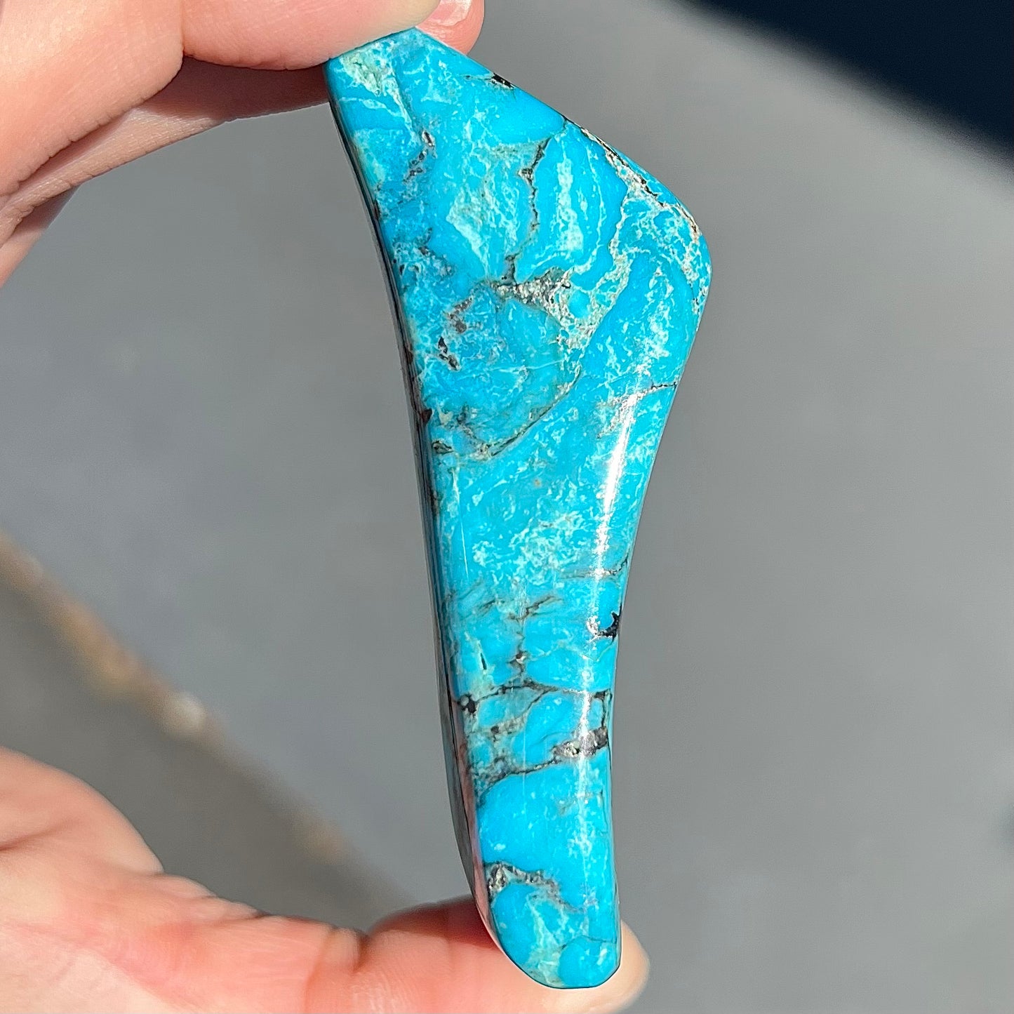 A large polished piece of Kingman turquoise. The stone is blue with black veining.