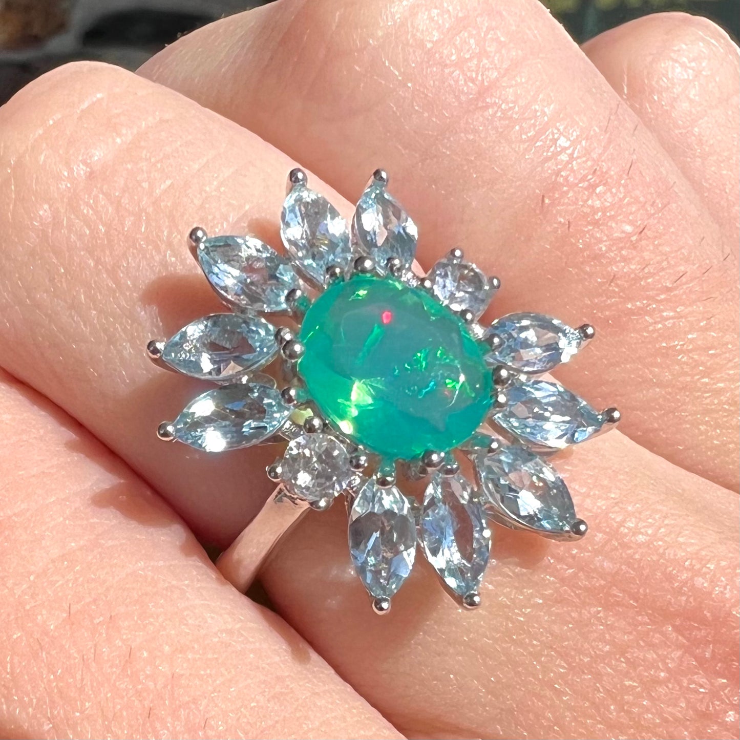 A faceted oval cut blue Ethiopian fire opal set in a sterling silver ring with marquise cut blue topaz stones.
