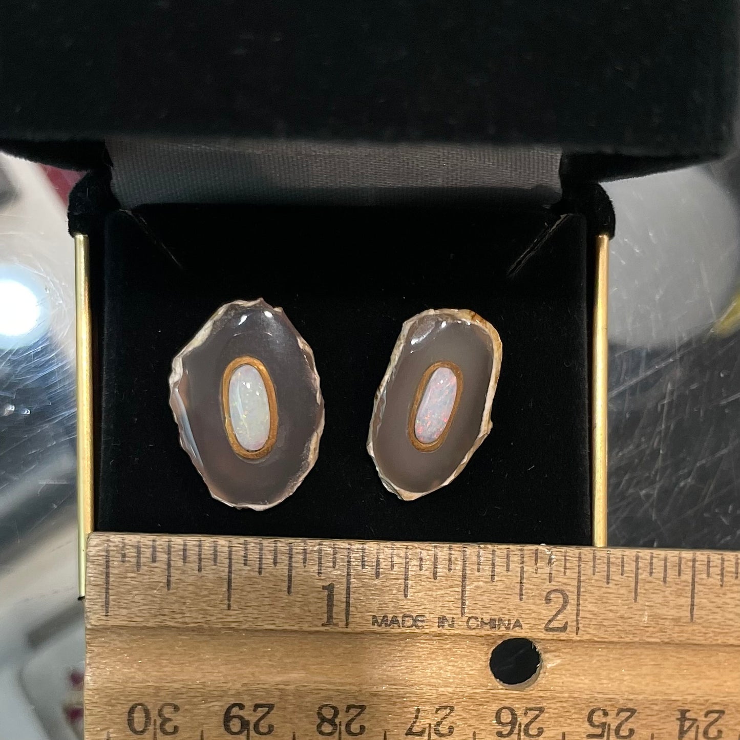 Earrings featuring oval cut white crystal opal cabochons set in slices of polished agate with yellow gold bezels.
