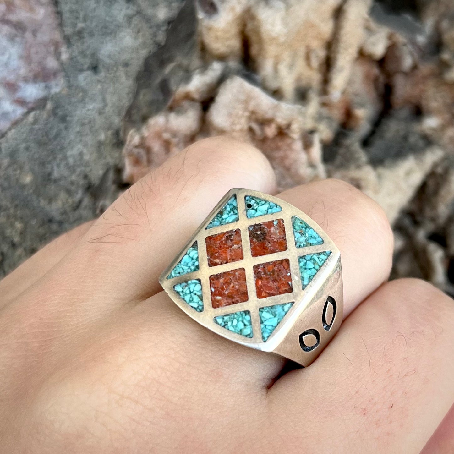 A men's sterling silver inlay ring set with sections of crushed blue turquoise and crushed red coral.