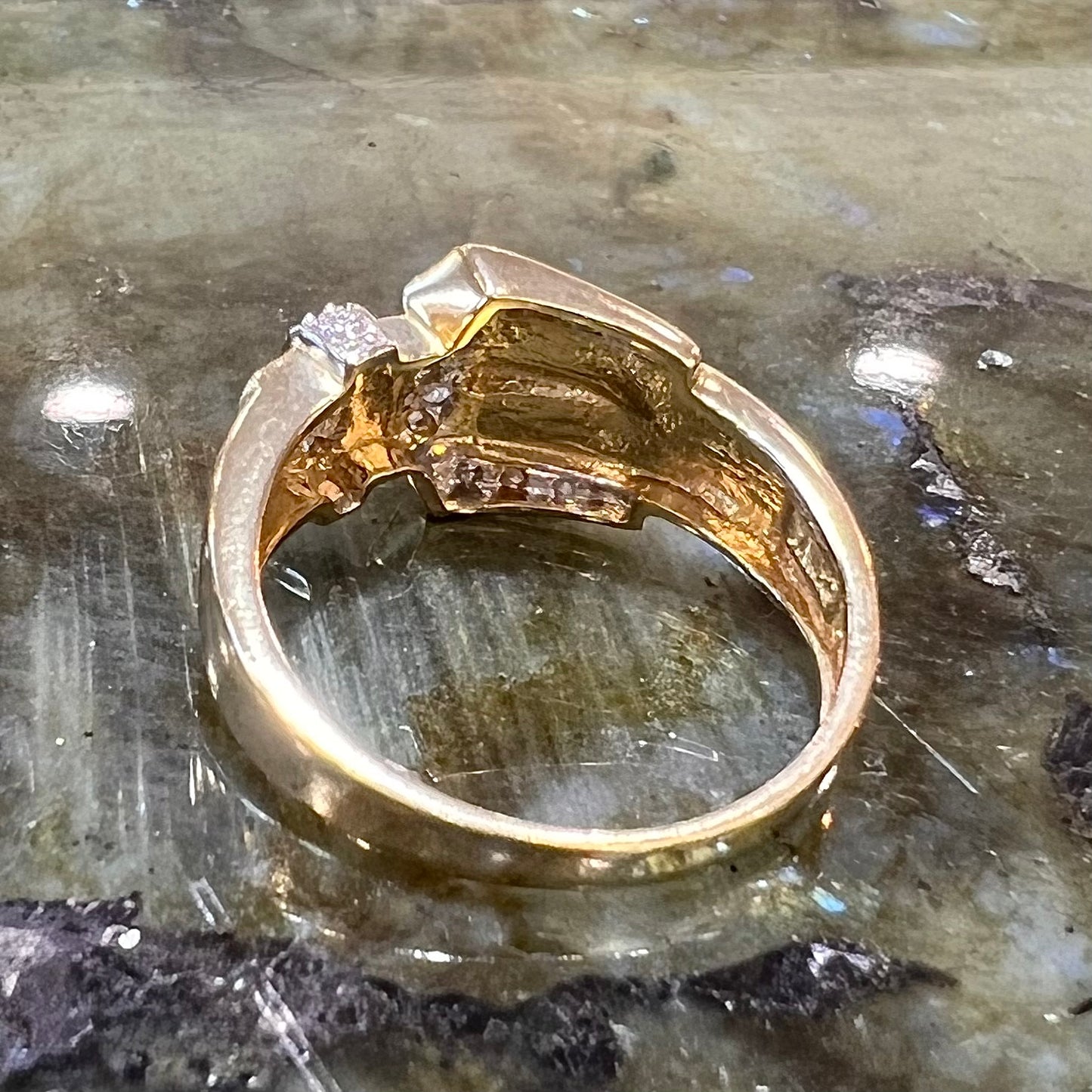 A yellow gold buckle ring set with round diamonds in the buckle.