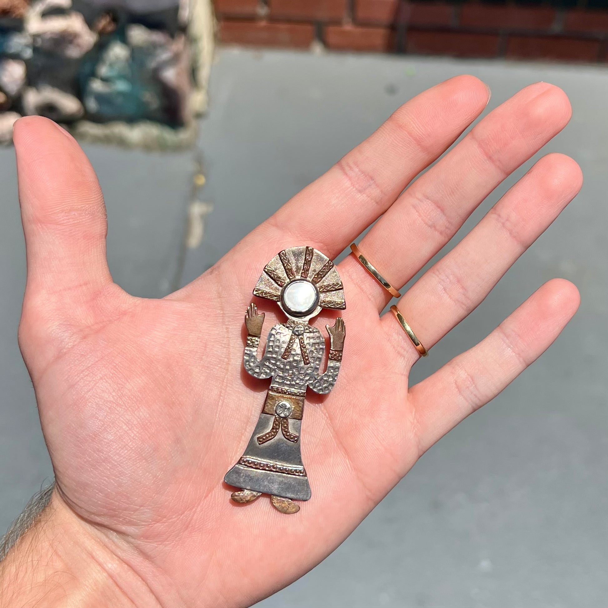 A handmade Navajo style silver pendant with copper highlights shaped like a Navajo Indian shaman.  There is a mother of pearl set as the shaman's face.