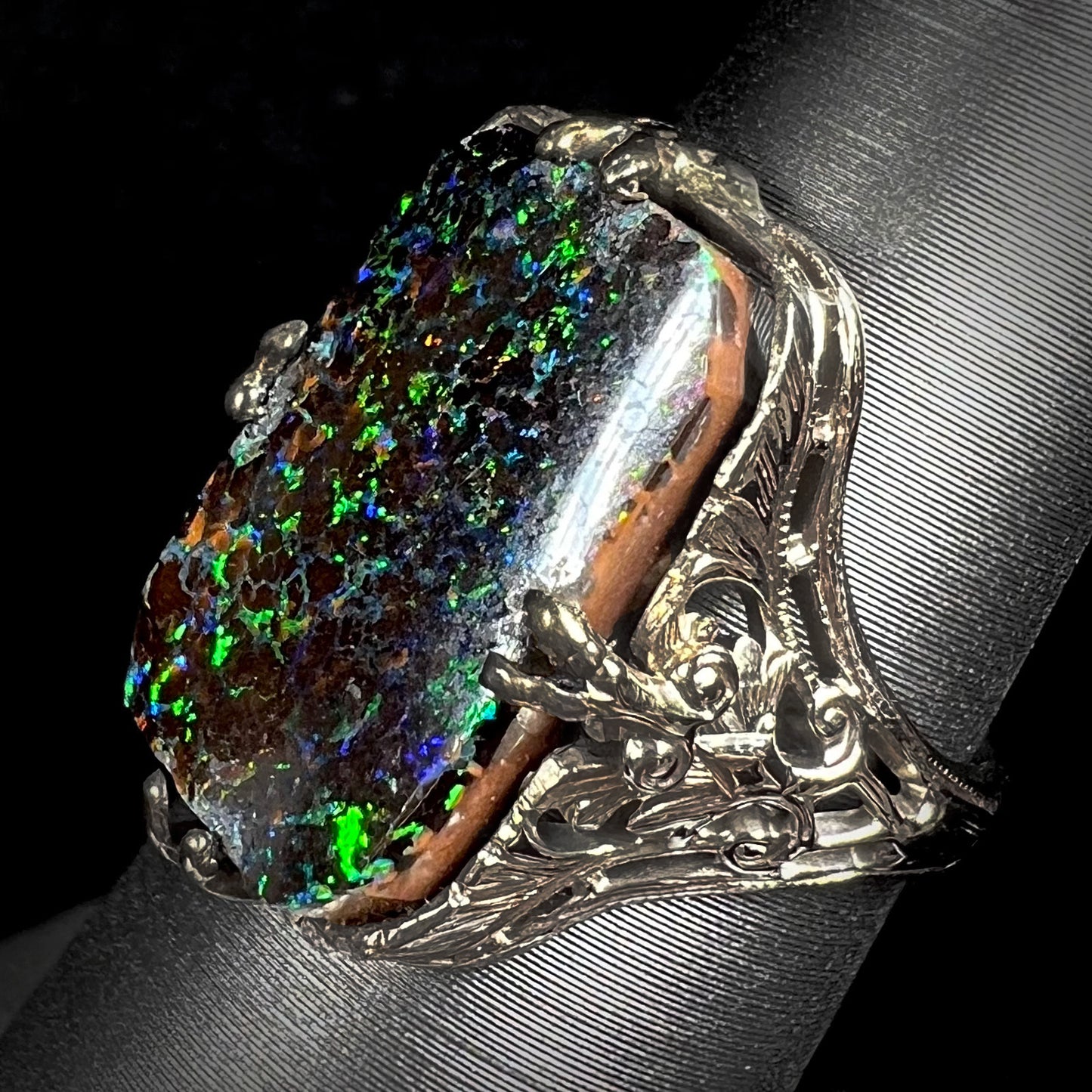 A vintage, white gold filigree unisex ring set with a natural black Koroit boulder opal.