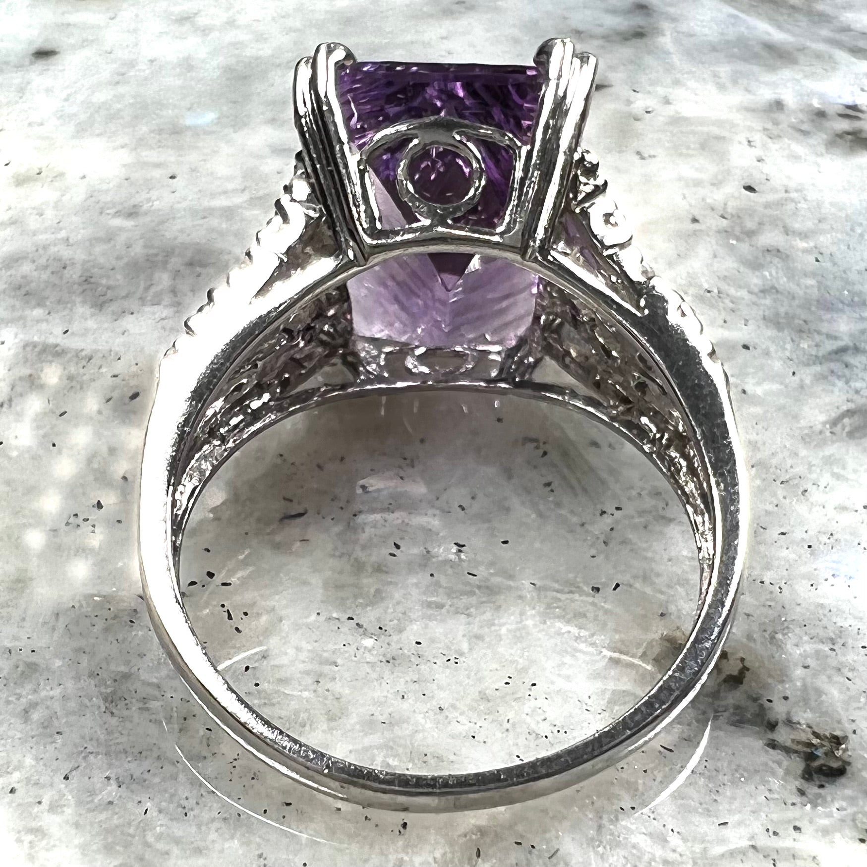 A white gold ladies ring set with an emerald laser cut amethyst and diamond chip accents.