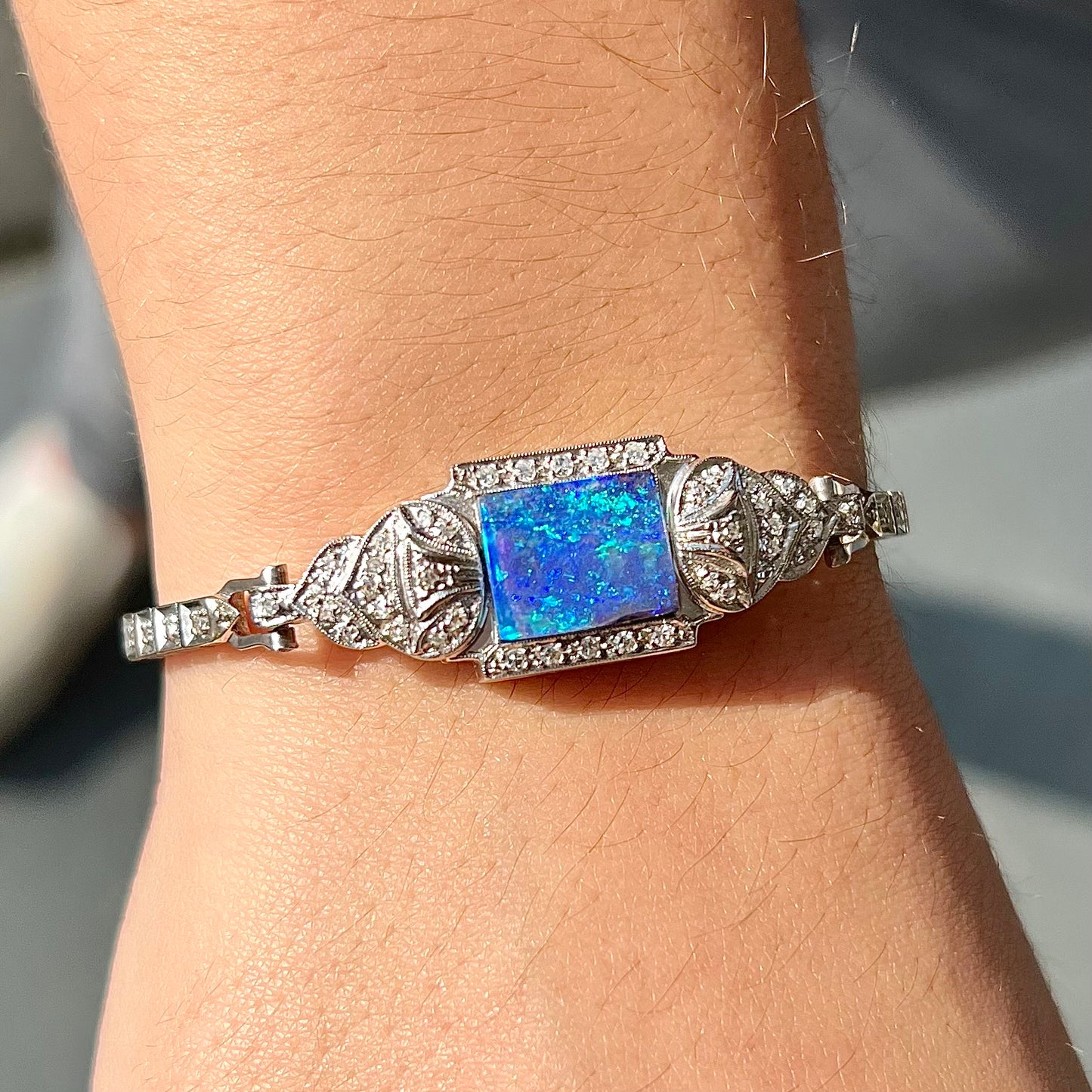 A vintage, art deco style white gold and diamond bracelet set with a rectangular shape black boulder opal stone.