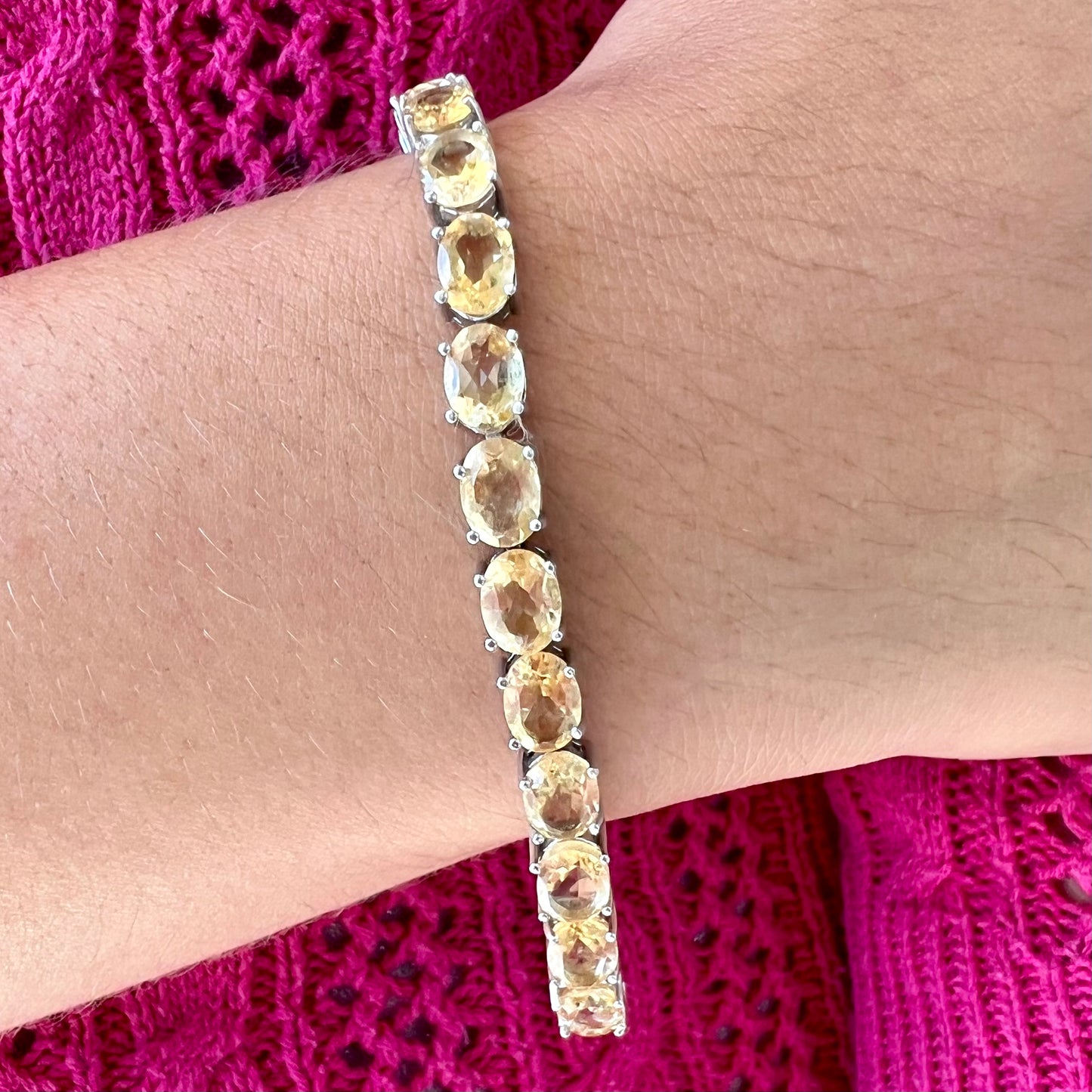 A sterling silver ladies' tennis bracelet set with faceted oval cut citrine stones.