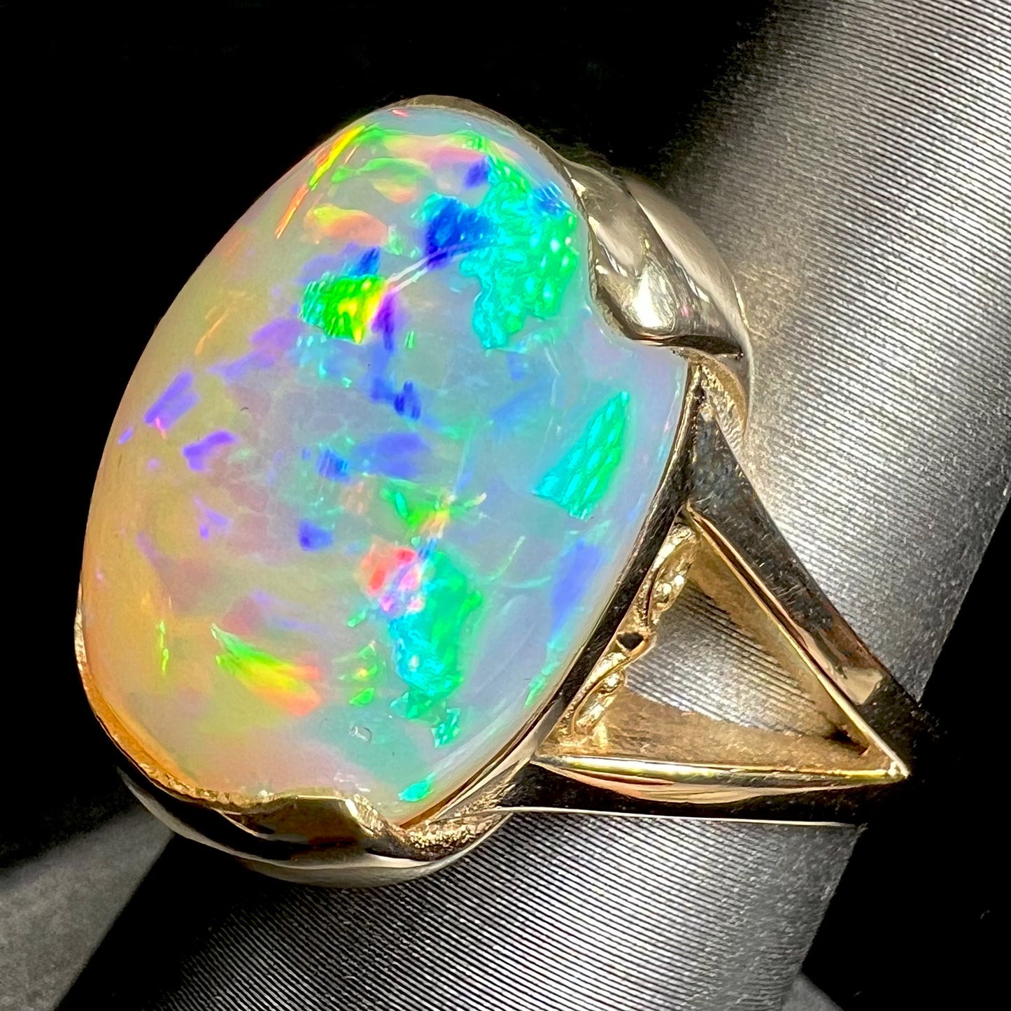 A ladies' yellow gold split shank ring half-bezel set with a barrel cabochon cut natural Ethiopian fire opal stone.
