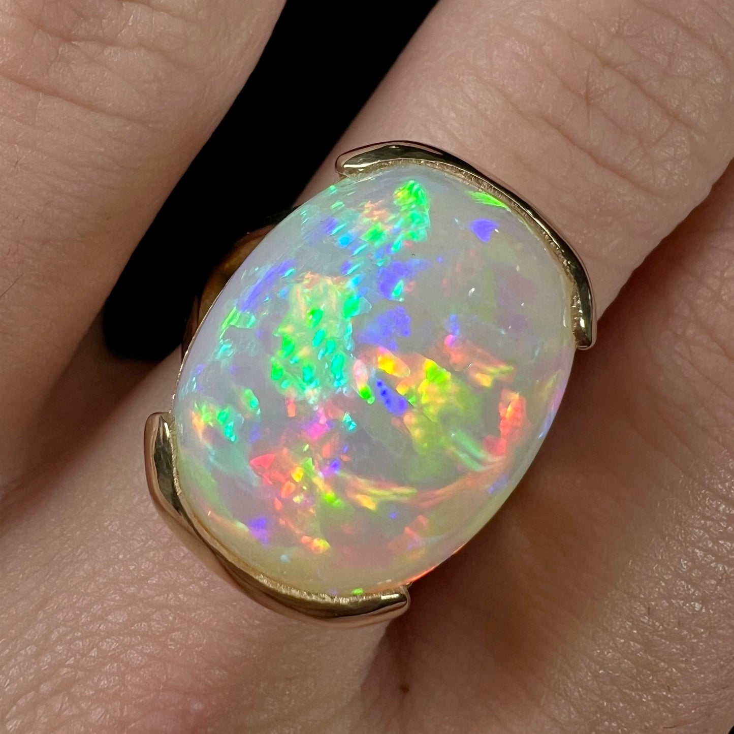 A ladies' yellow gold split shank ring half-bezel set with a barrel cabochon cut natural Ethiopian fire opal stone.