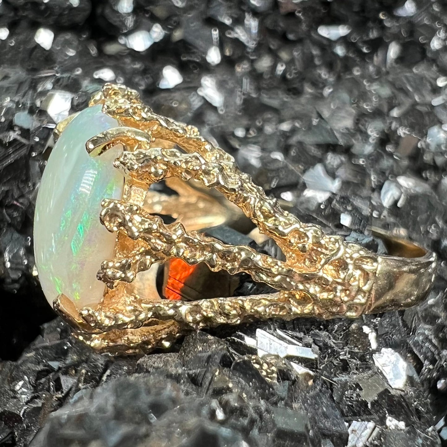 A yellow gold solitaire engagement ring set with an oval cabochon cut white crystal opal.