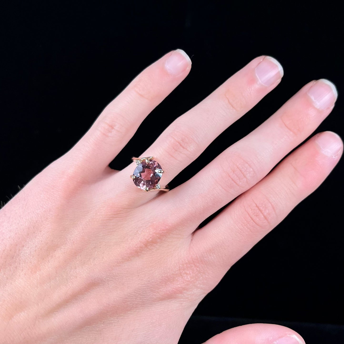 A ladies' yellow gold, faceted oval cut purple tourmaline ring set with diamond accents.
