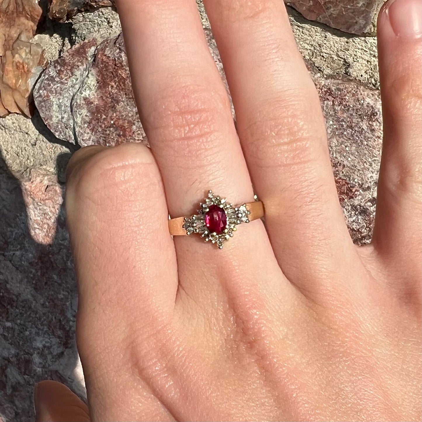 A yellow gold ring set with an oval cut red spinel and diamond rounds and baguettes.