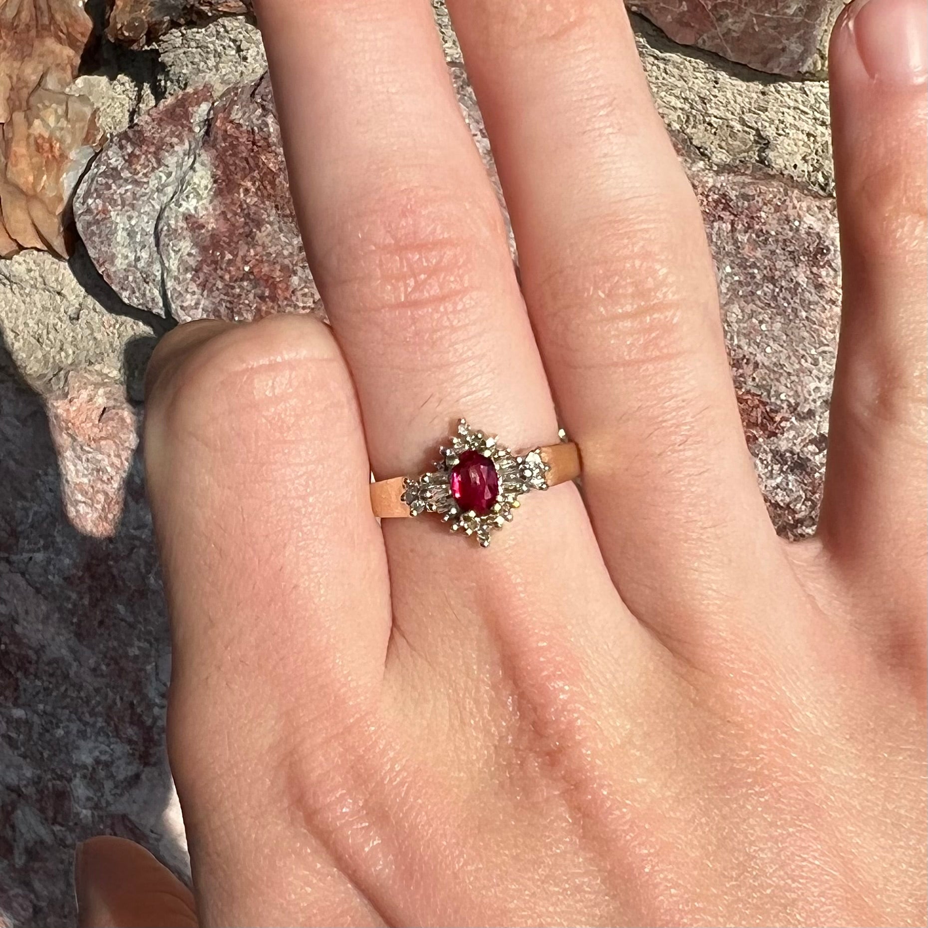 A yellow gold ring set with an oval cut red spinel and diamond rounds and baguettes.