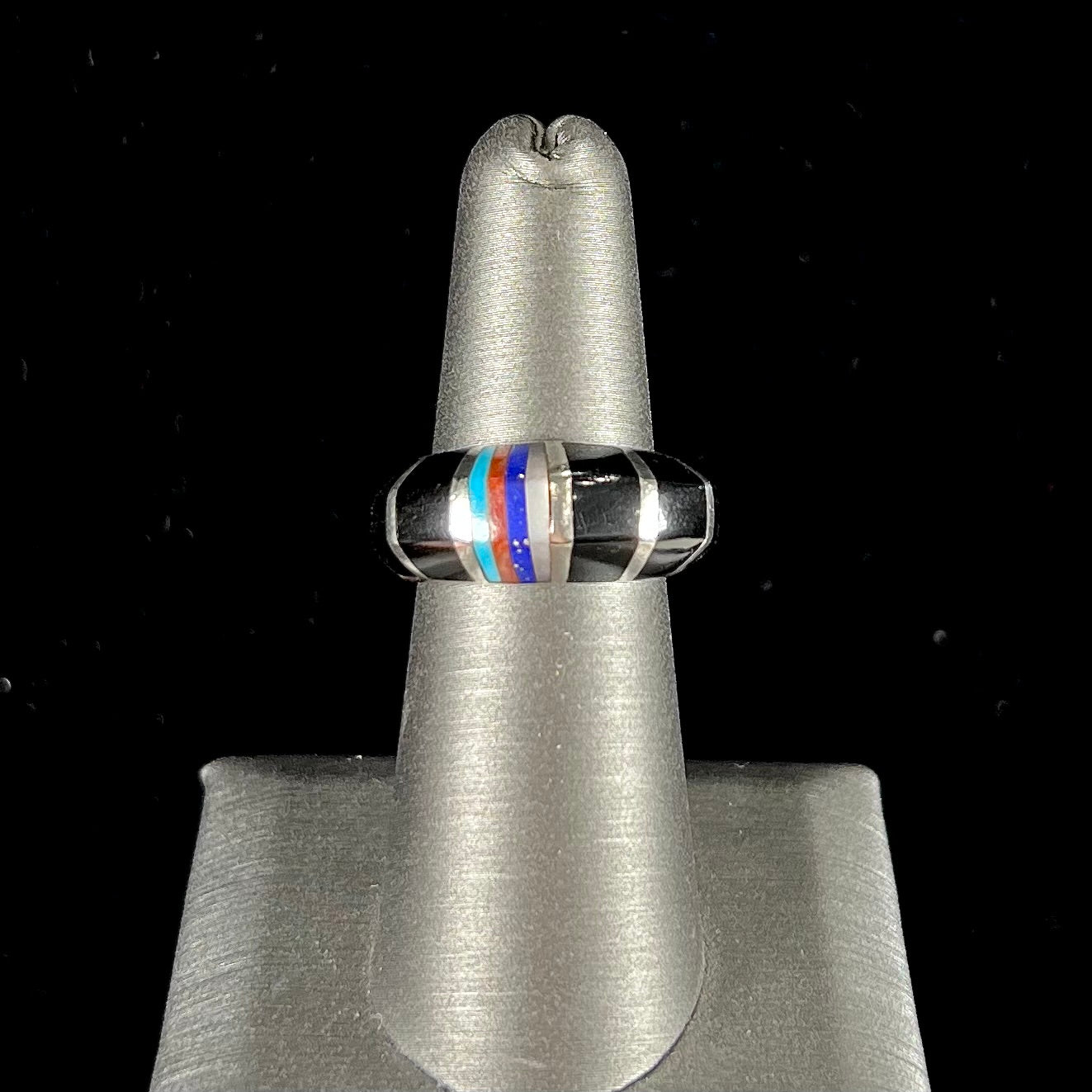 A sterling silver ring inlaid with onyx, turquoise, coral, lapis lazuli, and mother of pearl stones.