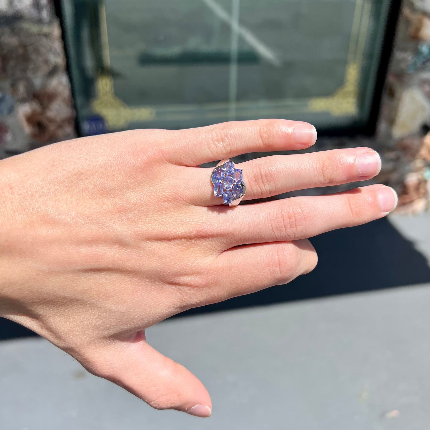 A sterling silver cluster ring prong set with seven faceted oval cut blue tanzanite stones.