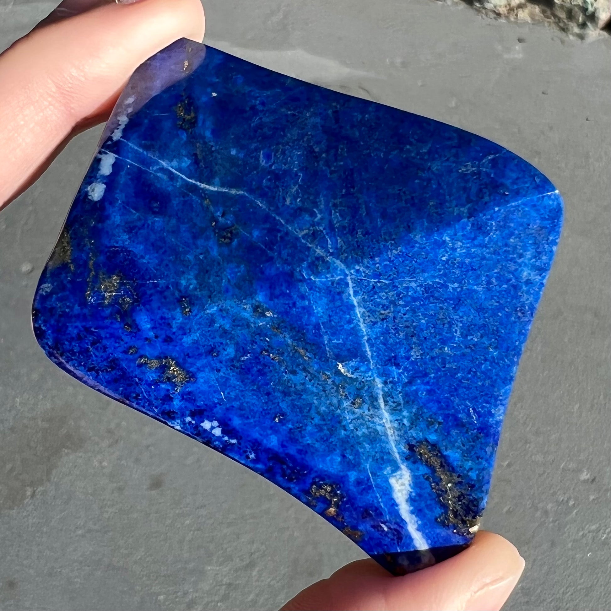 A loose polished sculpture made from royal blue lapis lazuli with golden pyrite inclusions.