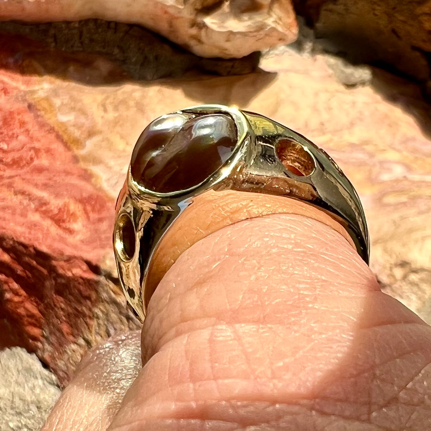 Men's rainbow fire agate ring set in yellow gold with champagne diamonds. The ring style has holes.