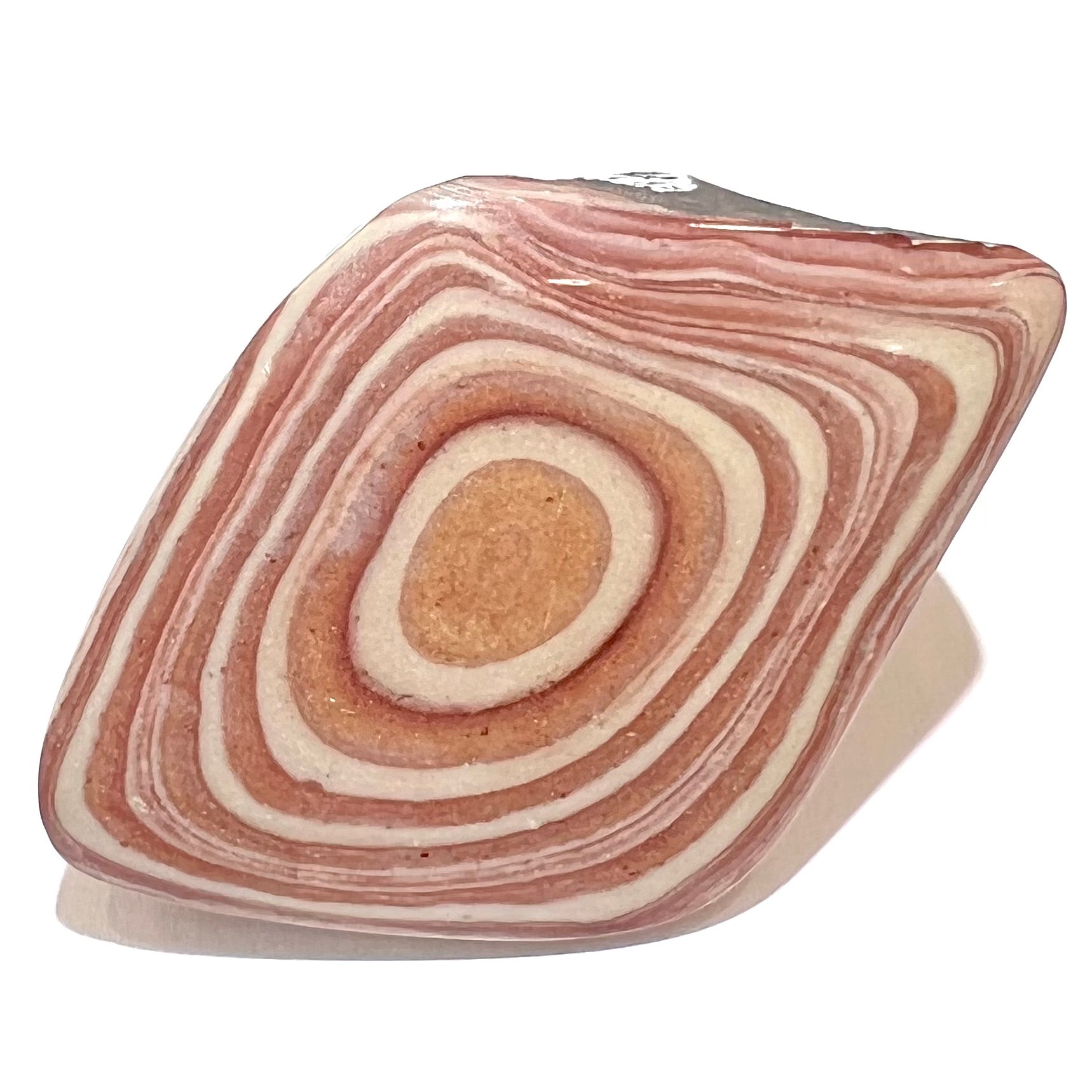 A polished piece of pinkish red picture jasper.  The stone displays a bull's eye pattern.