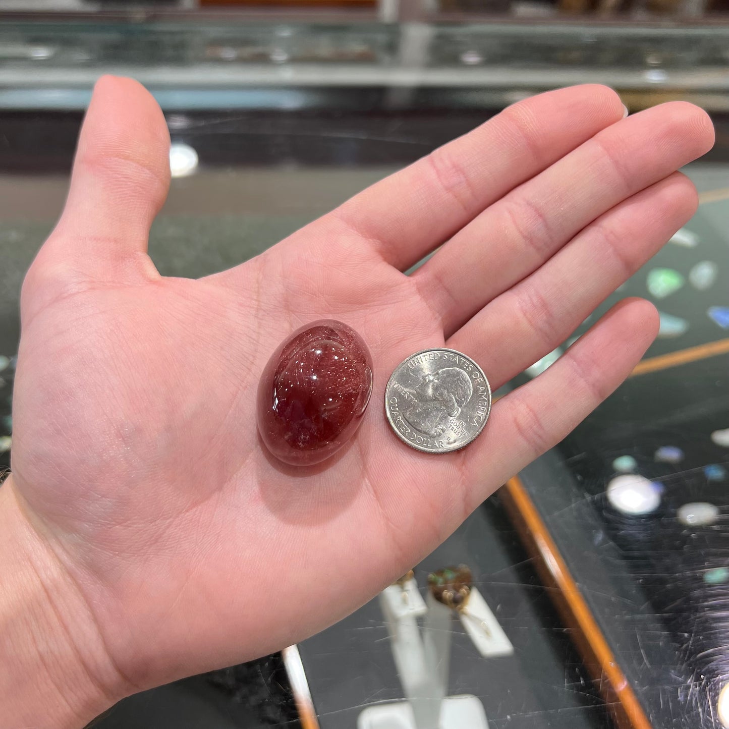 A large, oval cabochon cut strawberry quartz. The stone has a trapiche star-like pattern.