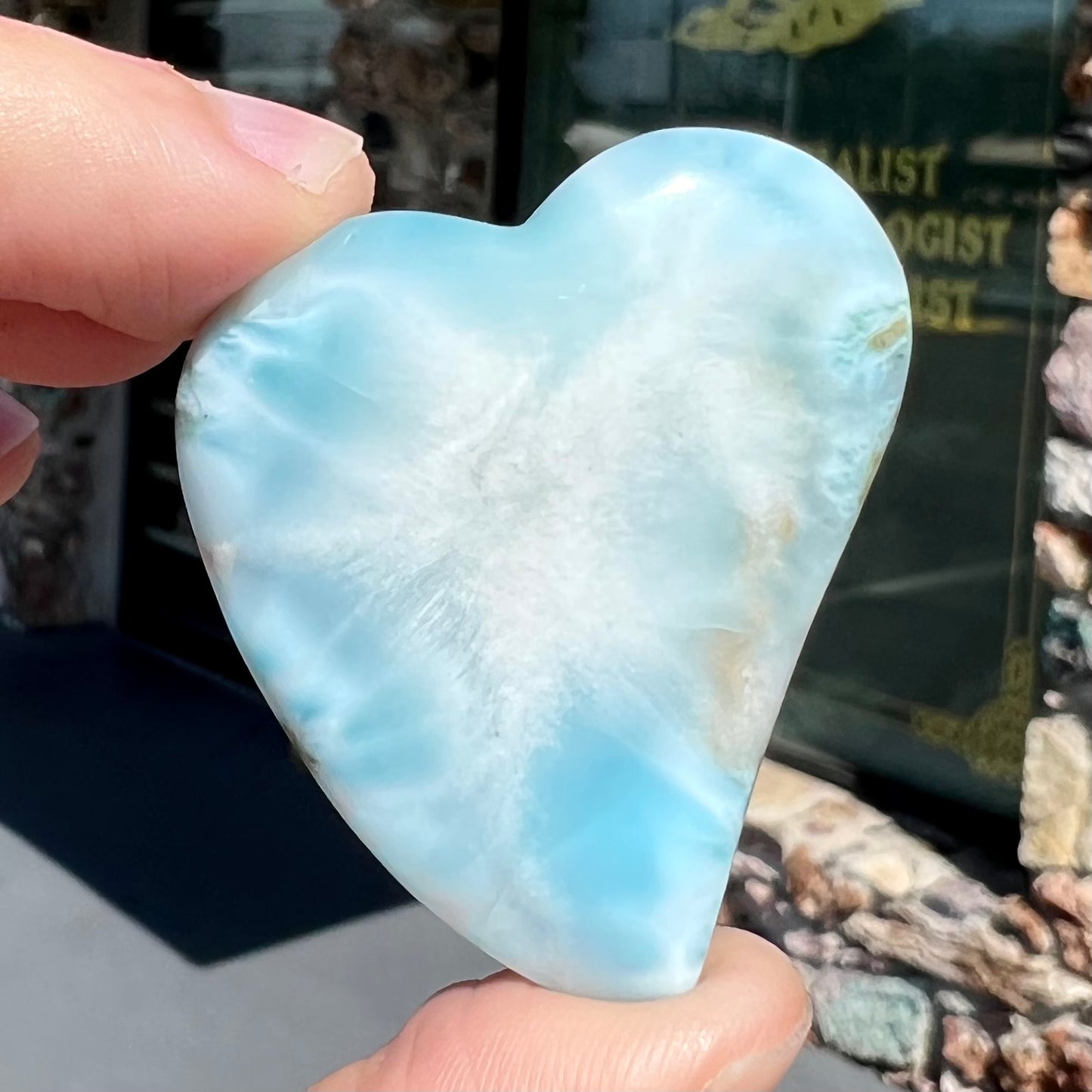 A loose, carved, heart shaped larimar stone. Predominant colors are blue and white.