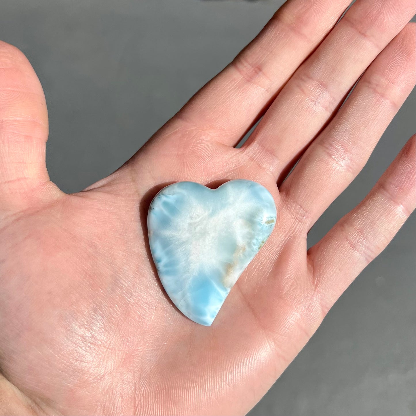 A loose, carved, heart shaped larimar stone. Predominant colors are blue and white.