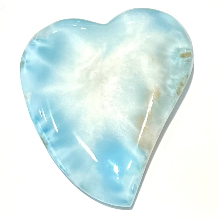 A loose, carved, heart shaped larimar stone. Predominant colors are blue and white.