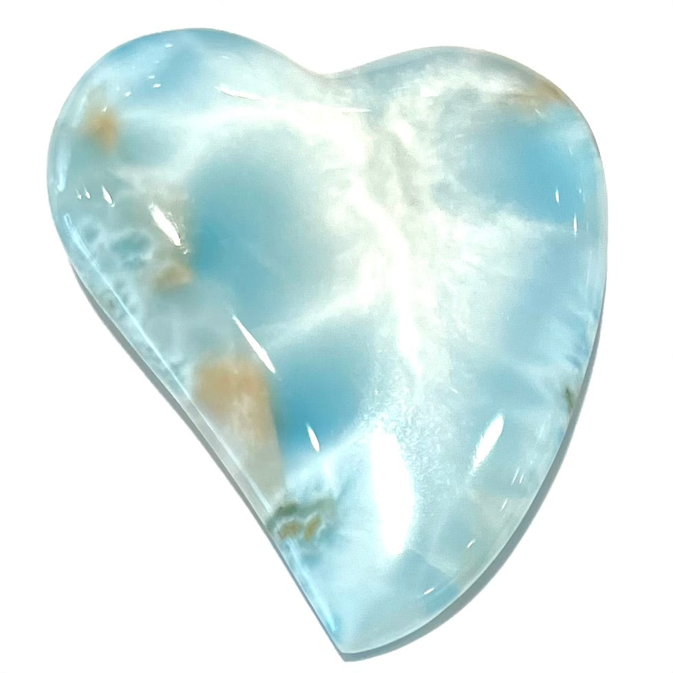 A loose, carved, heart shaped larimar stone. Predominant colors are blue and white.
