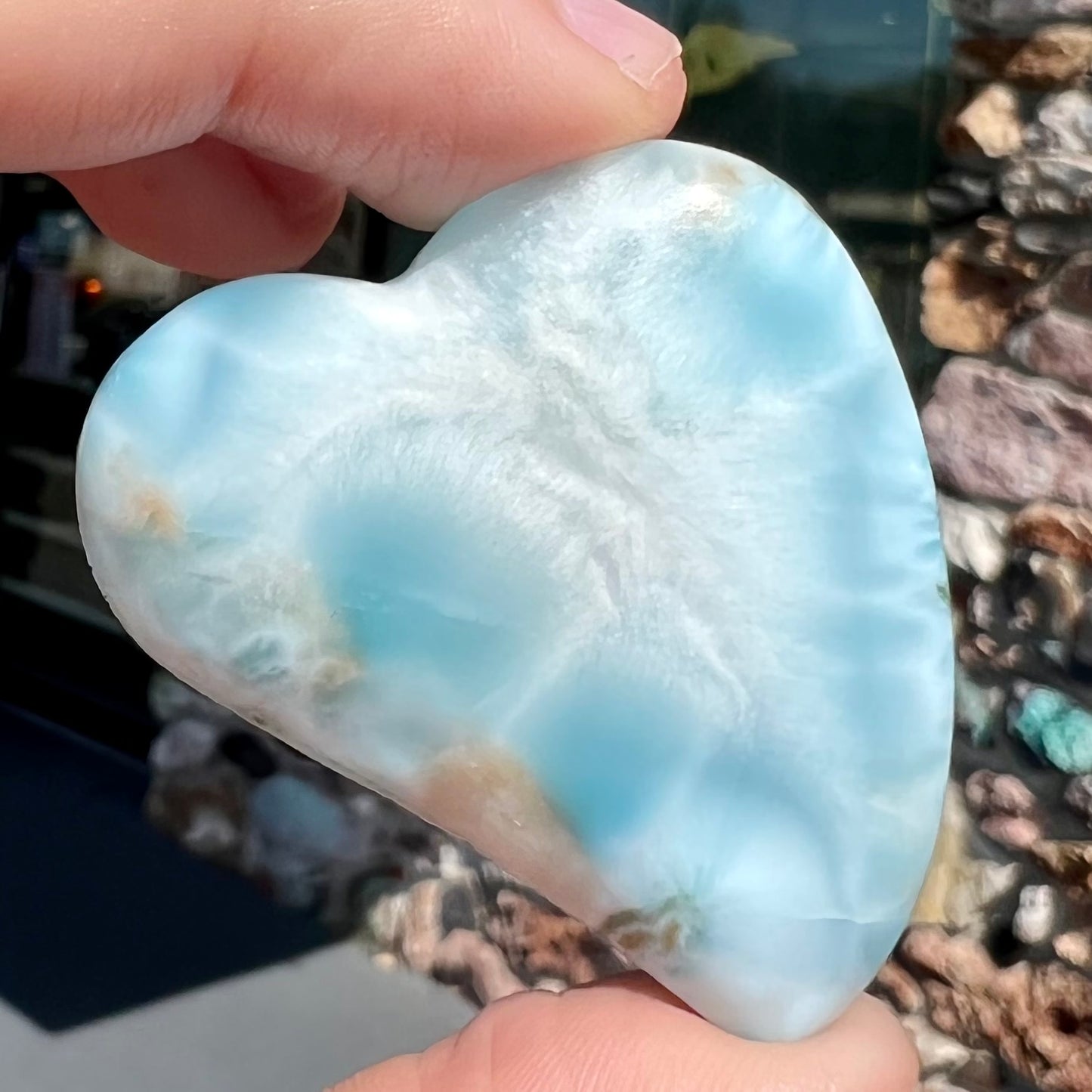 A loose, carved, heart shaped larimar stone. Predominant colors are blue and white.