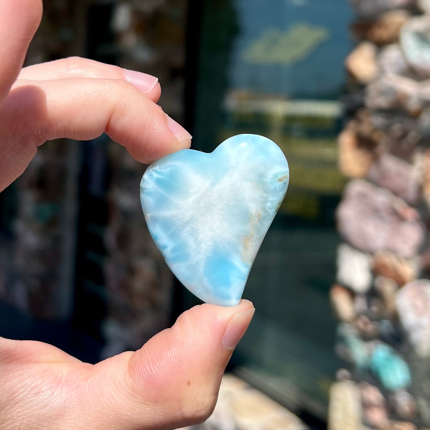 A loose, carved, heart shaped larimar stone. Predominant colors are blue and white.