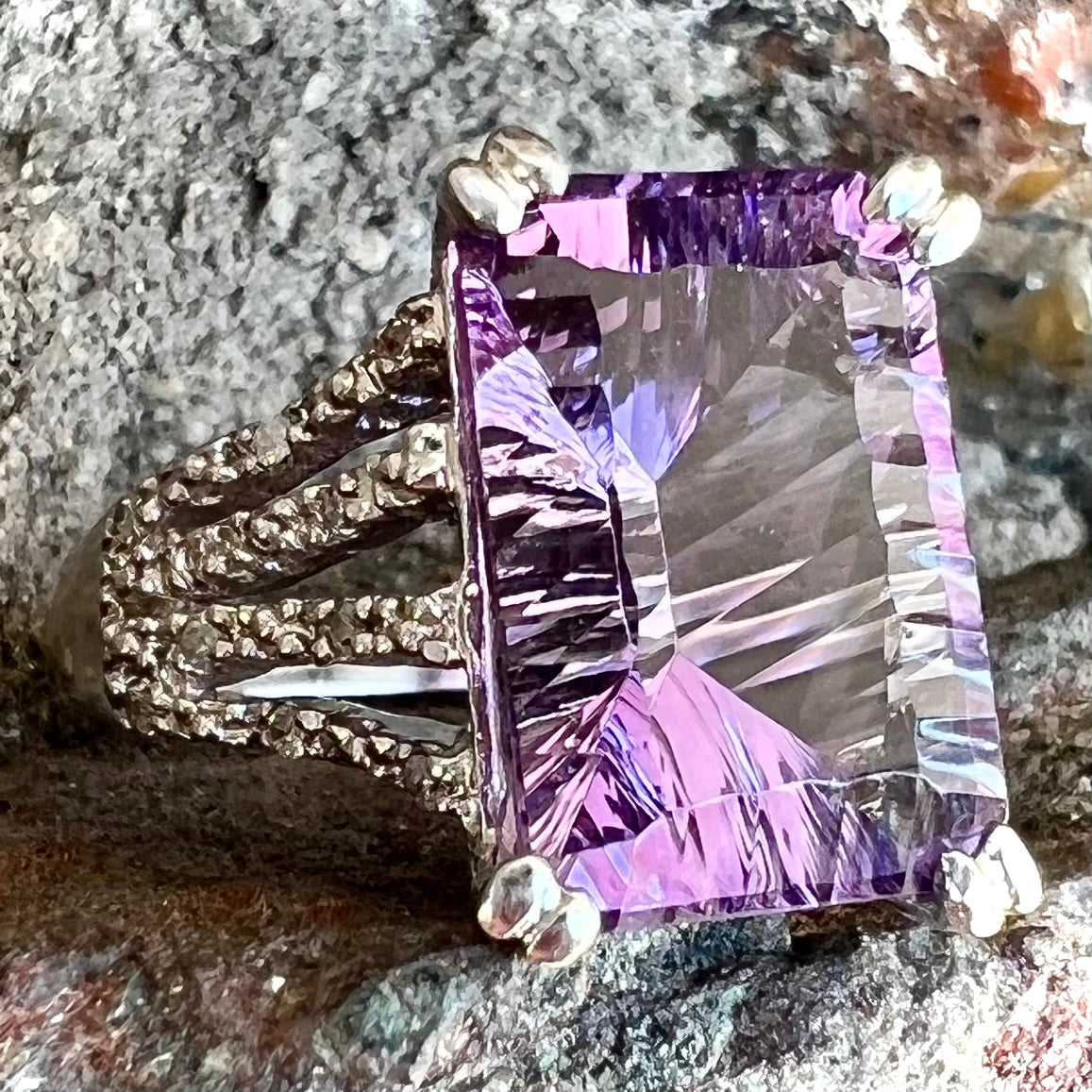 A white gold ladies ring set with an emerald laser cut amethyst and diamond chip accents.